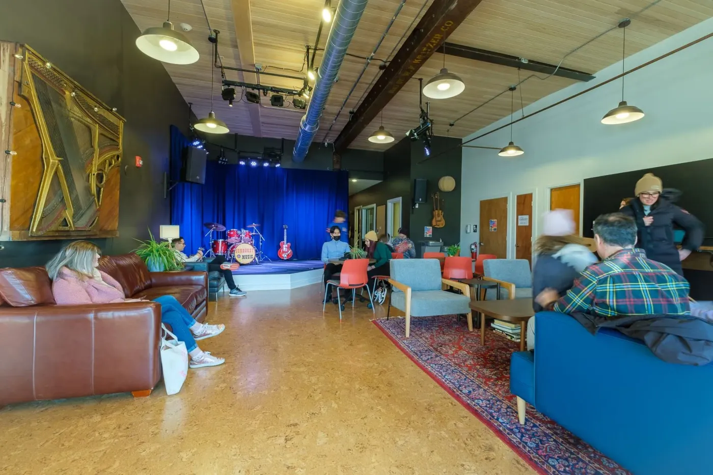Families relax on couches in the Sunburst lobby, with the concert stage and house drum kit in the background