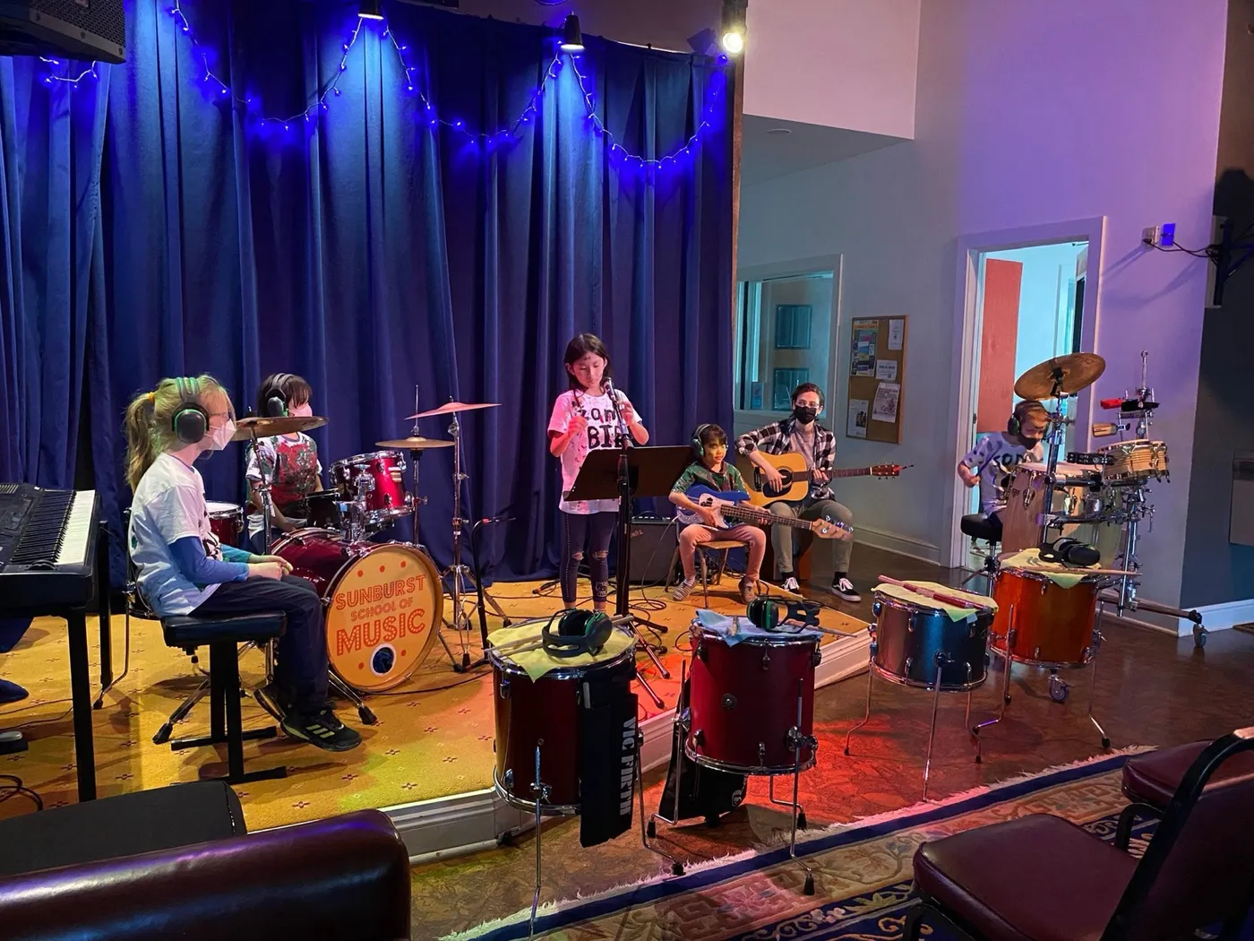 Campers perform together on the Sunburst stage with drums, keys, and guitars