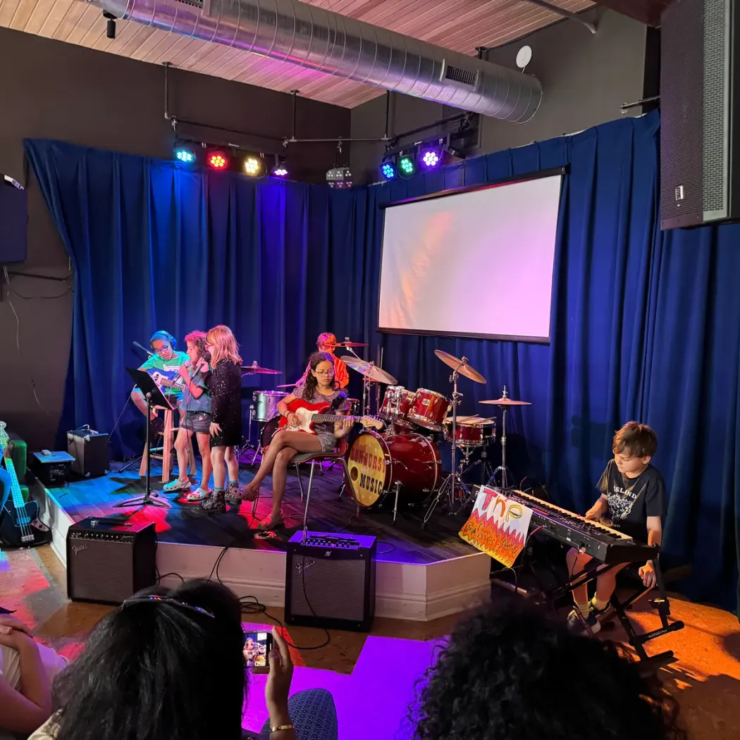 Kids in a camp band perform on the Sunburst stage while an audience watches