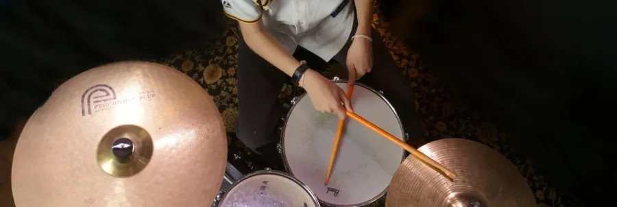 An overhead view of a drummer's sticks crossing the kit mid-groove
