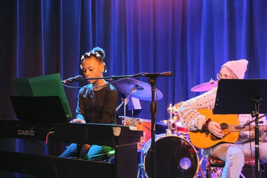 A young student plays keyboard on stage at a Sunburst recital