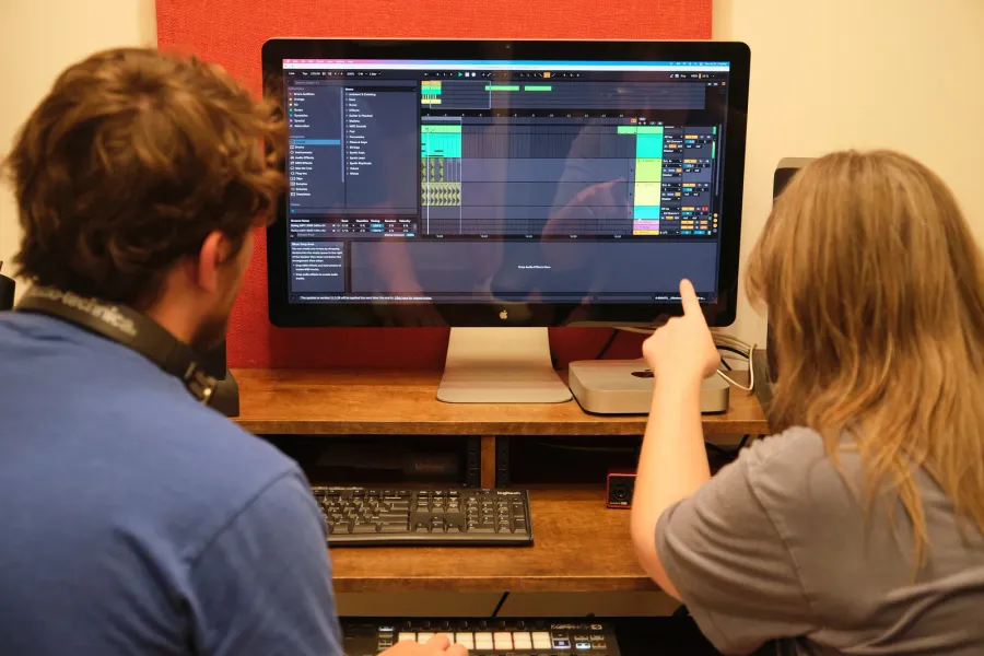 A student points out a section of the arrangement on screen during a production lesson