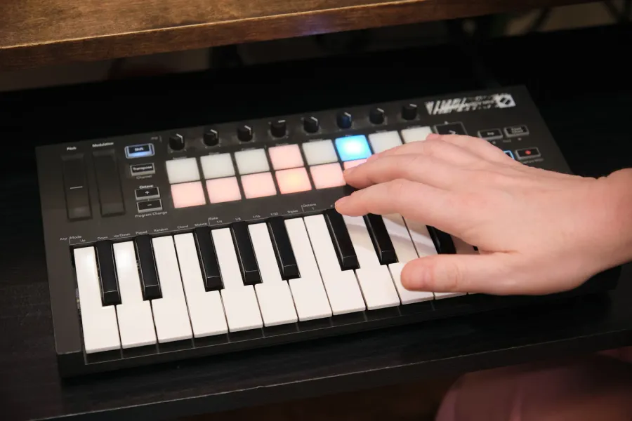 A student triggers lit pads on a MIDI keyboard in the studio