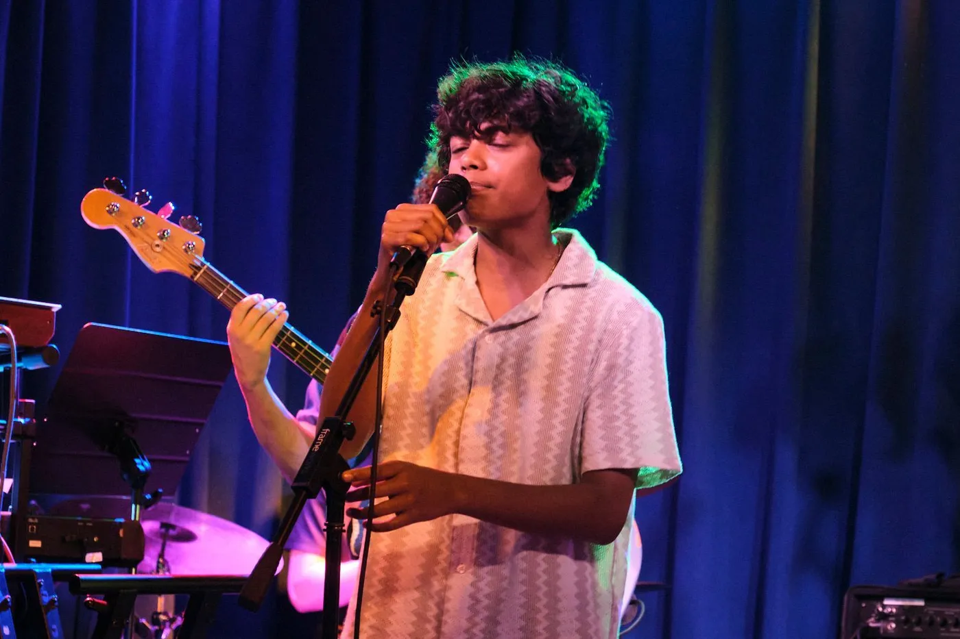 A teen singer performs at the microphone on the Sunburst stage